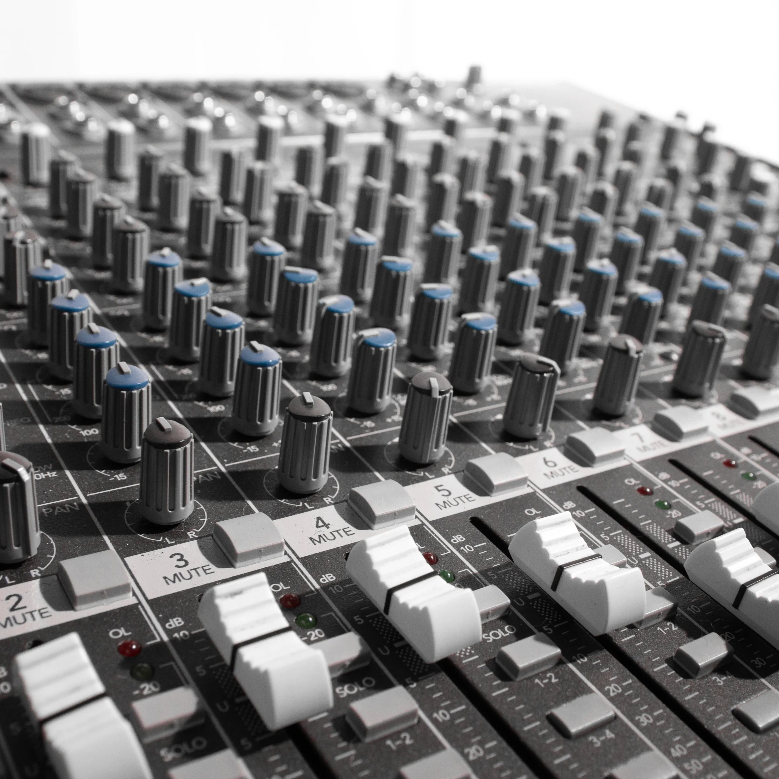 A close-up of a sound desk mixer with numerous knobs for adjusting audio settings.