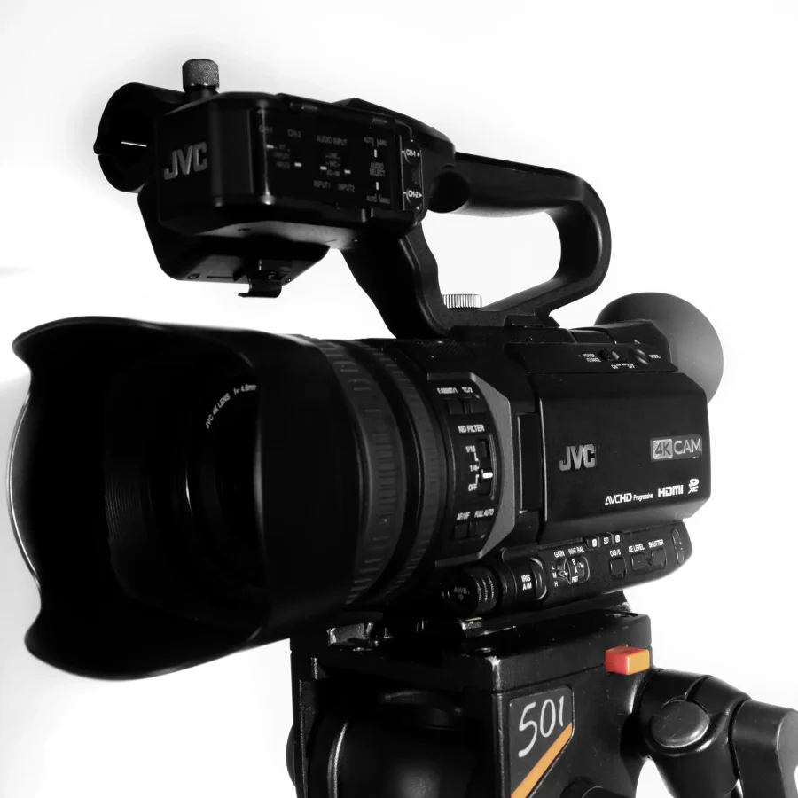 A tripod holds a JVC GY-HM250E 4K UHD camcorder, poised to record professional-grade video content.